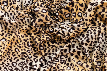 Background in the form of a knitwear product with a pattern similar to a leopard skin in cream brown with crumpled fabric