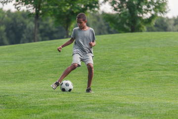 Obraz premium cute african american boy playing football on grass