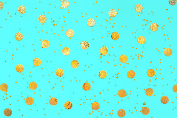 Photo of gold confetti sprinkles in different sizes on pastel cyan backdrop. Christmas pattern. Festive holiday background. for your projects. Celebration concept. Top view, flat lay