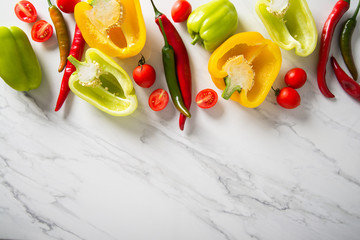 Fresh red, green, yellow sweet and hot peppers on white marble background. Healthy food, clean eating.	