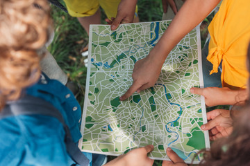 cropped view of kid pointing with finger at map near friends