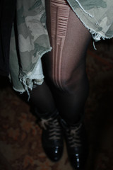 Legs of woman in torn tights, military skirt and boots