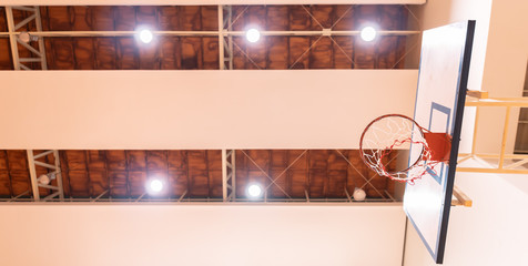 Low angle view of Basketball hoop in Gym with ceiling spotlight, Sport arena background with copy space