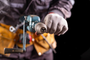 Production worker with tool belt. Drill in the hand of an employee.