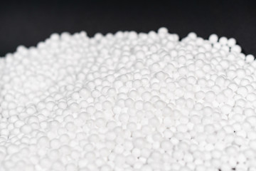 White Polystyrene foam beads on black background with copy space, waste cushioning material in luxury packaging