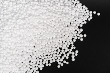 White Polystyrene foam beads on black background with copy space, waste cushioning material in...