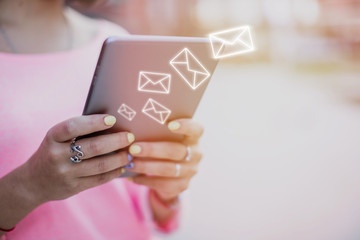 Send an e-mail on the Internet. Icons with an envelope on the background of hands holding a tablet.