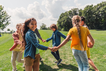 selective focus of happy multicultural kids holding hands