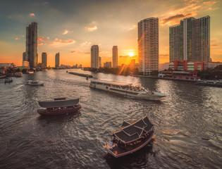Busy Chao Phraya River with Passenger Boats and Skyscrapers at Sunset as Seen from Taksin Bridge in Bangkok, Thailand