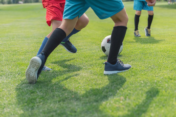 Fototapeta na wymiar cropped view of boys playing football on grass