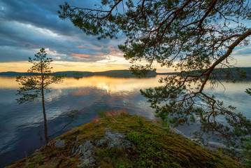 Sunset on the edge of the shore of the island on lake Ladoga .