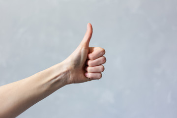 Close-up of female hand show thumb up, on white background.