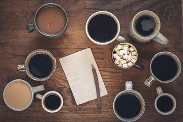 Many cups of coffee on wooden table, top view. Notebook with white sheets on a wooden table, flatlay. Autumn concept - keeping a diary, entry plan.