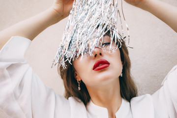 Girl with big red lips in white blouse, gold earrings and silver metal foil tinsel strips like...