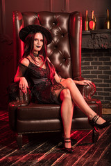Fototapeta na wymiar Charming witch in a dark room on Halloween