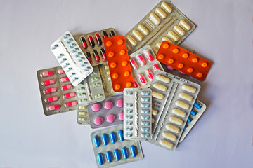 A pile of pills in blister packs. Blister packs full of multi-colored pills. Close-up on a light background. Full colored pills package. Pharmaceutical blister pack. Pack of pills with tablets.