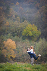 Fototapeta na wymiar Couple having fun outside, autumn vibes. Boy lifting girl in air.