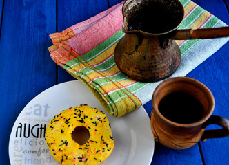 Homemade Turkish coffee, a Turk for cooking, a ceramic cup, a kitchen napkin, donuts on a white...