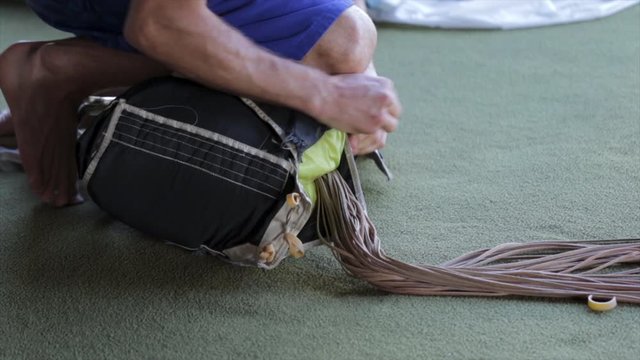 Skydiver parachute packing close up. Hands folding parachute lines getting ready to jump out of airplane. Skydive equipment close up. Skydive packer and rigger. 