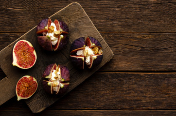 figs, cream cheese, honey on a cutting board, dark rustic background. Top view