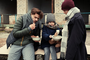 Poor young family with bread on dirty street