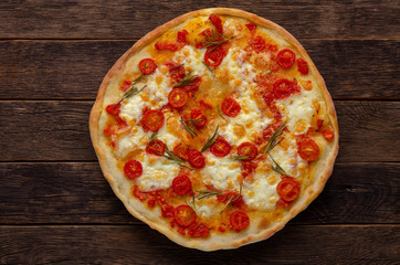 Italian pizza on wooden background. Cherry tomatoes, parmesan cheese and rosemary.