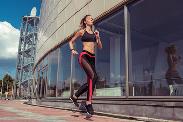 Fototapeta na wymiar Sports beautiful girl in summer runs jogging, sportswear top leggings, morning bright sunny day. Active lifestyle, fitness motivation workout. In movement, a woman is strong and hardy.