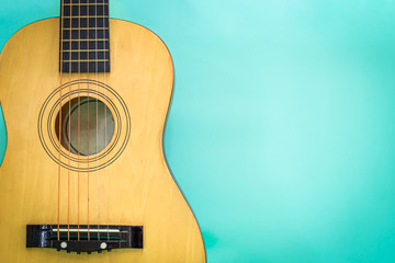 Acoustic guitar resting against a green background