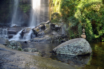 tropical waterfall with a totem and sunray