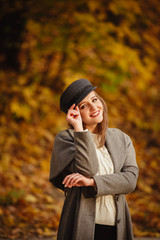 Autumn mood. Romantic woman weared in beige cloak walk in a park on background of beautifull autumn leaves. Smile. fall coming. Brown-haired girl with long hairs. Playing with Yellow leaves in hands