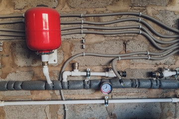 Closeup of manometer, pipes and faucet valves of heating system in a boiler room.
