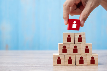 Business man hand placing or pulling Red wooden block with white person icon on the building. People, Business, Human resource management, Recruitment, Teamwork, strategy and leadership Concepts