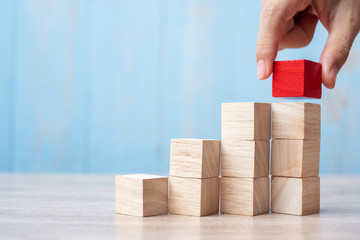 Businessman hand placing or pulling Red wooden block on the building. Business planning, Risk...