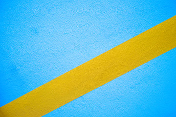 Diagonal broad golden yellow stripe on a blue empty surface.