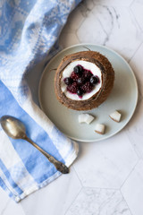Berry dessert with yogurt in a cup of coconut on a light background. Blackberries, raspberries, blueberries, black currants. Blue napkin