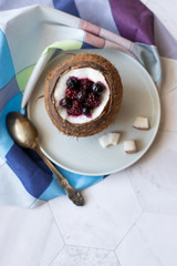 Berry dessert with yogurt in a cup of coconut on a light background. Blackberries, raspberries, blueberries, black currants. Blue napkin