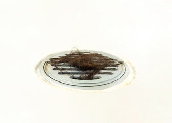hair loss clogged drain close up on white floor in bathroom, blurred photo