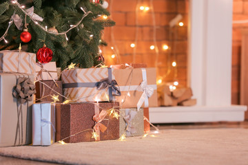 Beautiful Christmas gifts under fir tree on floor in room