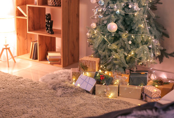 Beautiful Christmas gifts under fir tree on floor in room