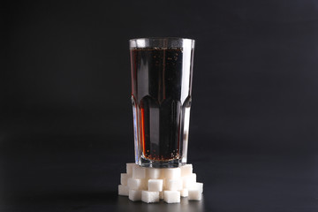 Glass of fresh cola and sugar on dark background