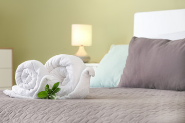 Fototapeta na wymiar Soft clean towels rolled in shape of snail on bed