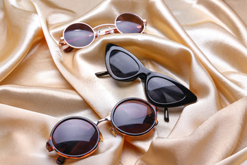 Different stylish sunglasses on color background