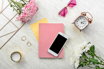 Modern mobile phone with notebook and female accessories on light background