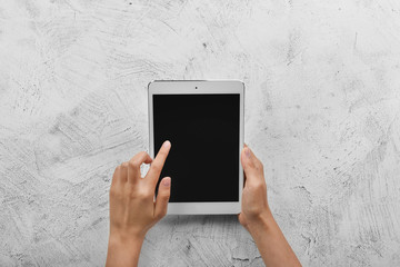 Female hands with modern tablet computer on light background