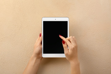 Female hands with modern tablet computer on color background