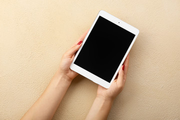 Female hands with modern tablet computer on color background