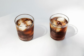Glasses of cold cola on light background