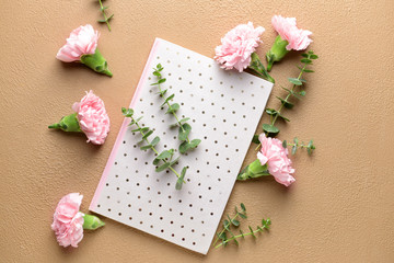 Beautiful carnation flowers and greeting card on color background