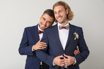 Portrait of happy gay couple on their wedding day against light background
