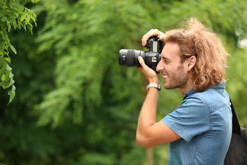 Young male photographer with camera outdoors